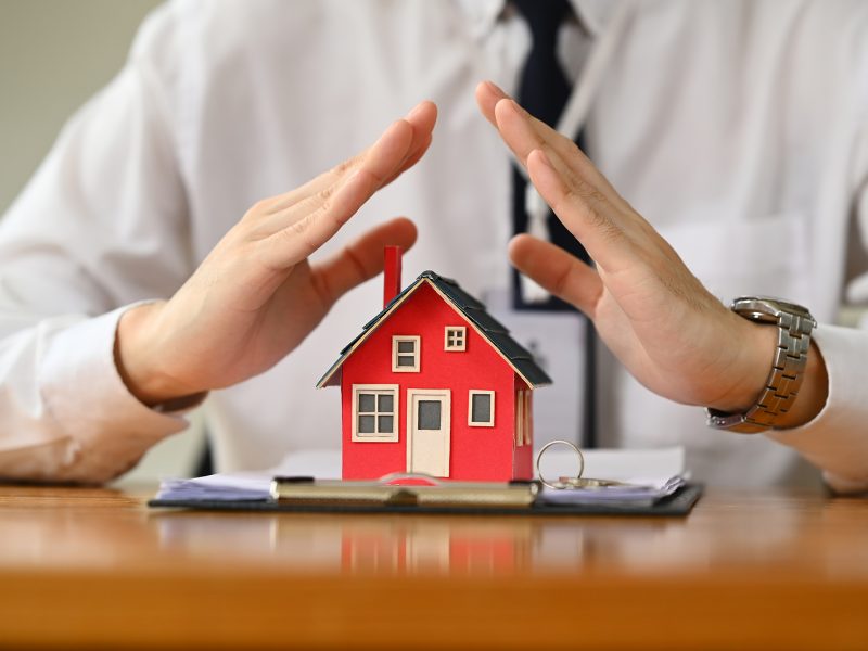 Man hands protecting over little house. Property insurance and security concept